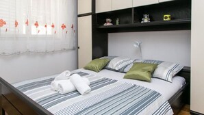 A bedroom with a bed, pillows, a nightstand, and a window with curtains. - Apartment Angelina - Three Bedroom Apartment With Balcony and Sea View (Dubrovnik)