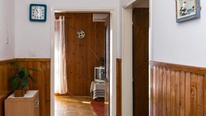 A hallway with wooden paneling, a clock, a plant, and a television in the background. - Apartment Angelina - Three Bedroom Apartment With Balcony and Sea View (Dubrovnik)