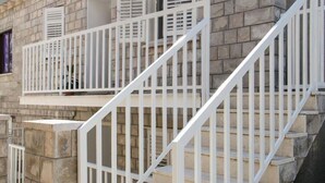 A staircase with white railings leading to a stone building with multiple windows and shutters. - Apartment Angelina - Three Bedroom Apartment With Balcony and Sea View (Dubrovnik)