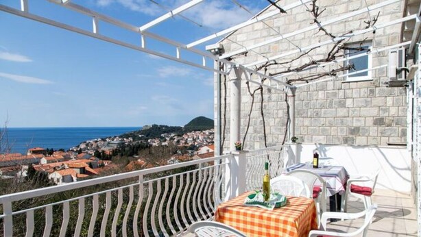A balcony with a table and chairs, overlooking a coastal town. - Apartment Angelina - Three Bedroom Apartment With Balcony and Sea View (Dubrovnik)