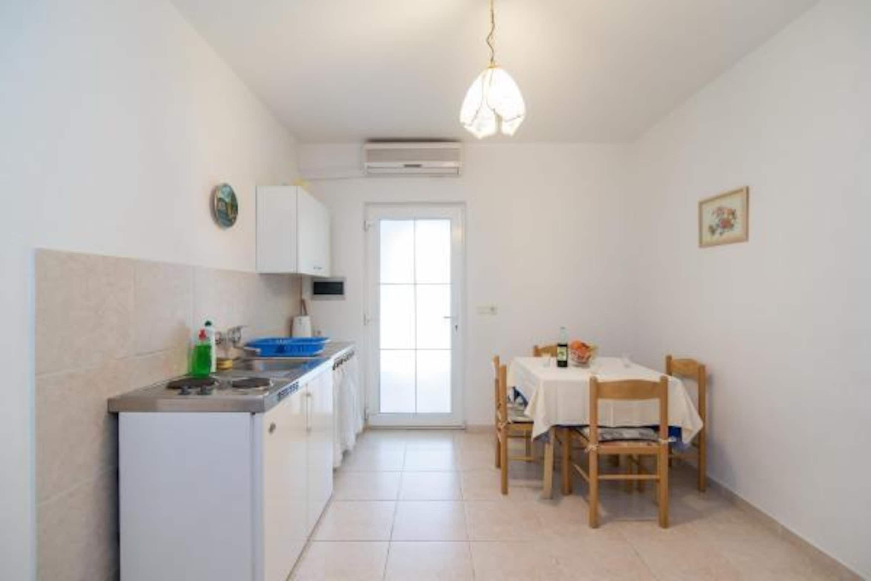 A compact kitchen with a refrigerator, stove, and dining table with chairs.