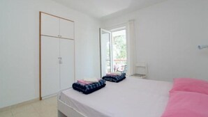 A bedroom with a bed, a wardrobe, and a window with a view of greenery outside. - Apartments Boguvila - Two-bedroom Standard Apartment With Terrace - (Supetar)