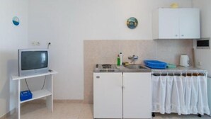 A compact kitchen with a built-in refrigerator, a small sink, and a television on a stand. - Apartments Boguvila - Two-bedroom Standard Apartment With Terrace - (Supetar)