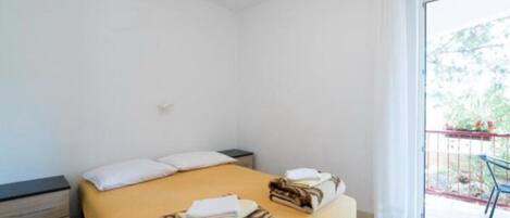 Une chambre à coucher avec un lit, une table de chevet et un balcon équipé d’une chaise.
