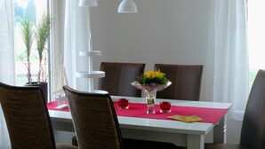 A dining area with a white table, brown chairs, a vase with flowers, and two pendant lights. - Heathside Family Retreat (Wietzendorf)
