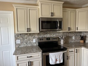 Modern kitchen with white cabinetry, stainless steel appliances, and a granite countertop.