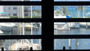 Un puerto deportivo con varias embarcaciones amarradas, un edificio de techo rojo y un cielo azul despejado.