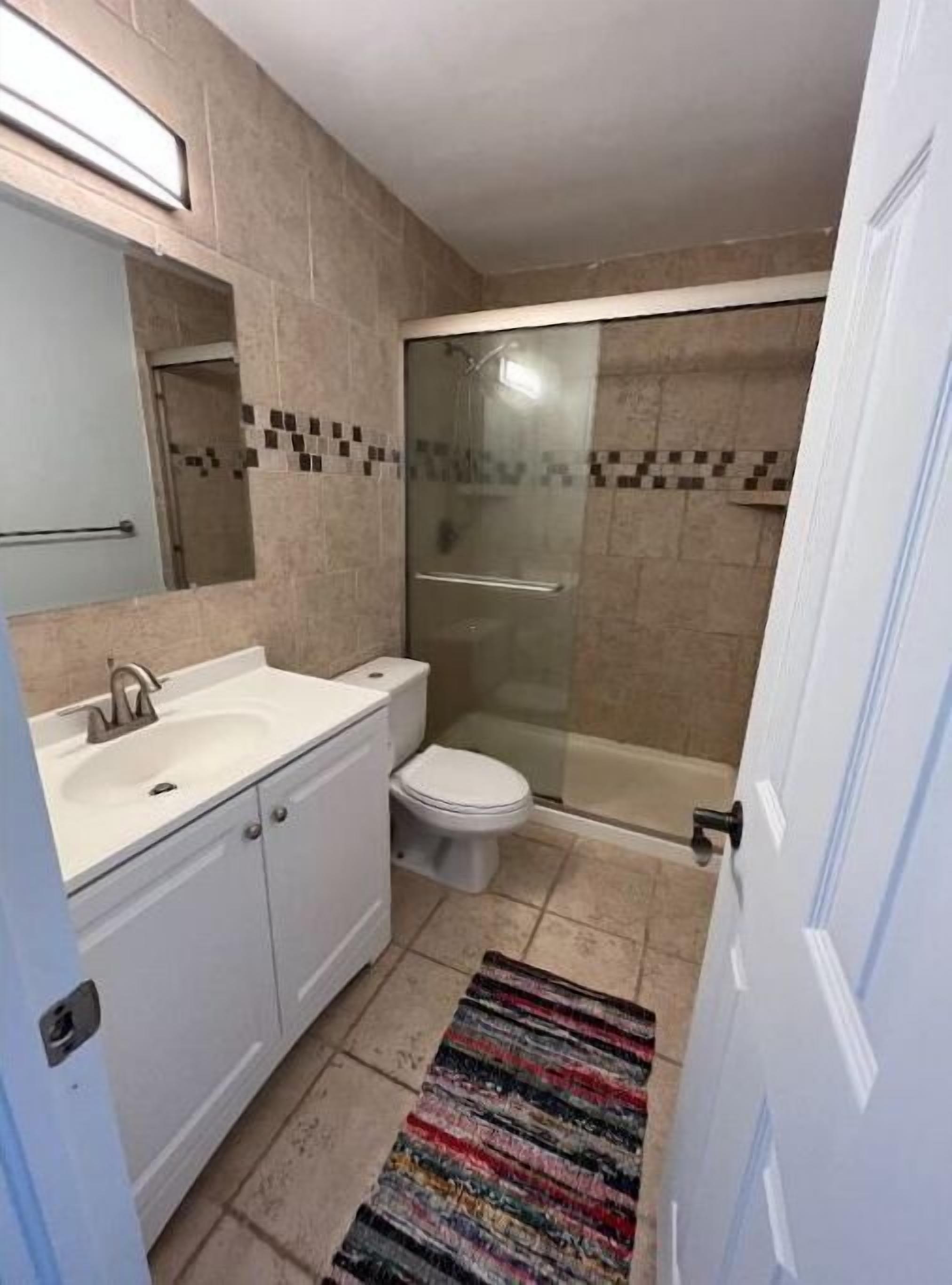 A bathroom with a white sink, toilet, and glass shower enclosure.