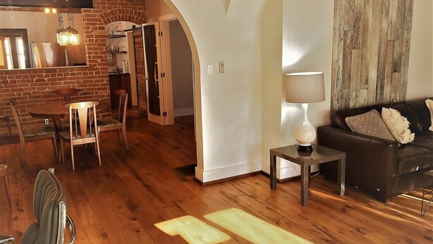 Una sala de estar con un sofá, una lámpara y un comedor con sillas y una mesa.