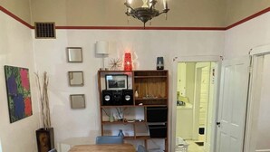 Comedor con una mesa de madera, sillas, una lámpara de araña y una estantería con diversos objetos.