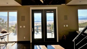 Une pièce spacieuse dotée d’une grande porte-fenêtre coulissante donnant sur un balcon avec vue sur les montagnes.