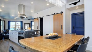 A modern kitchen with a large wooden dining table, black chairs, and a bowl of fruit. - 2 story condo w/ balconies, hovering above the action of the downtown scene. (Salida)