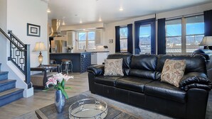 A modern living room with a black leather sofa, a glass coffee table, and a staircase leading to an upper level. - 2 story condo w/ balconies, hovering above the action of the downtown scene. (Salida)