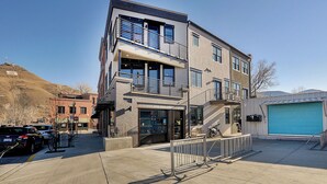 A modern multi-story building with a glass entrance, a blue garage door, and a metal fence in front. - 2 story condo w/ balconies, hovering above the action of the downtown scene. (Salida)
