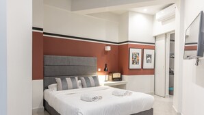 A modern hotel room with a large bed, a bedside table, a TV, and a door leading to a bathroom. - 85 sqm  in the Heart of Athens w/Rooftop Deck (Athens)