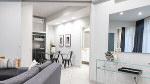 A modern living room with a grey sofa, a dining table with chairs, and a kitchen area in the background. - 85 sqm  in the Heart of Athens w/Rooftop Deck (Athens)