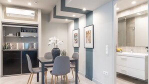 A modern kitchen with built-in appliances, a dining area with a table and chairs, and a bathroom with a large mirror and sink. - Fantastic Central Athens Suite with Rooftop Deck (Athens)