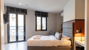 A modern bedroom with a large bed, a TV, a window with blinds, and a balcony. - Superb Central Athens Suite with Rooftop – Perfect for 5 Guests, 85sqm (Athens)