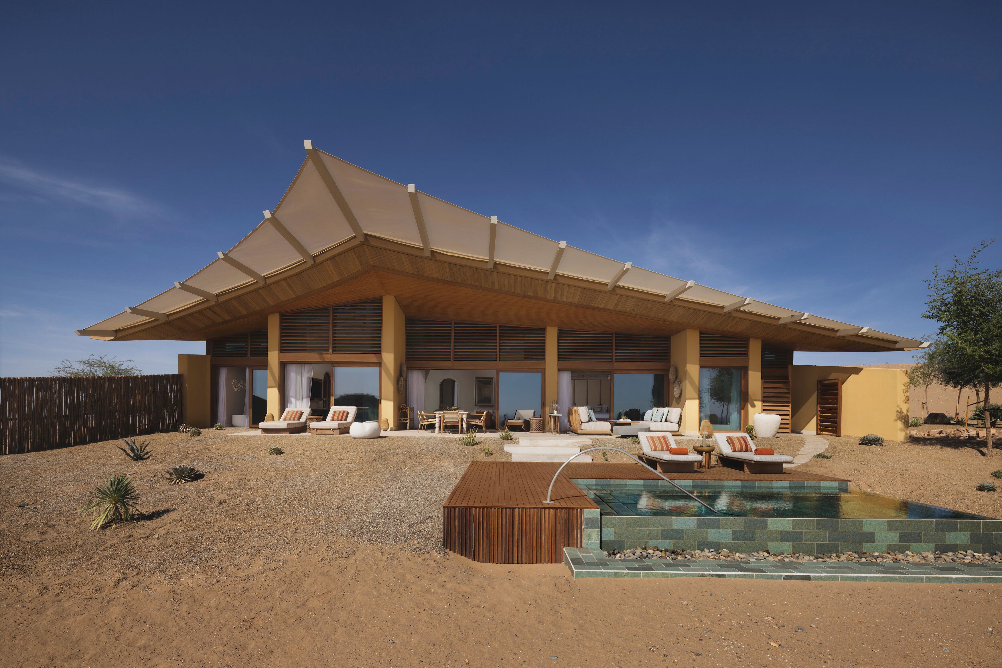 A modern house with a large covered patio, outdoor seating, and a swimming pool.