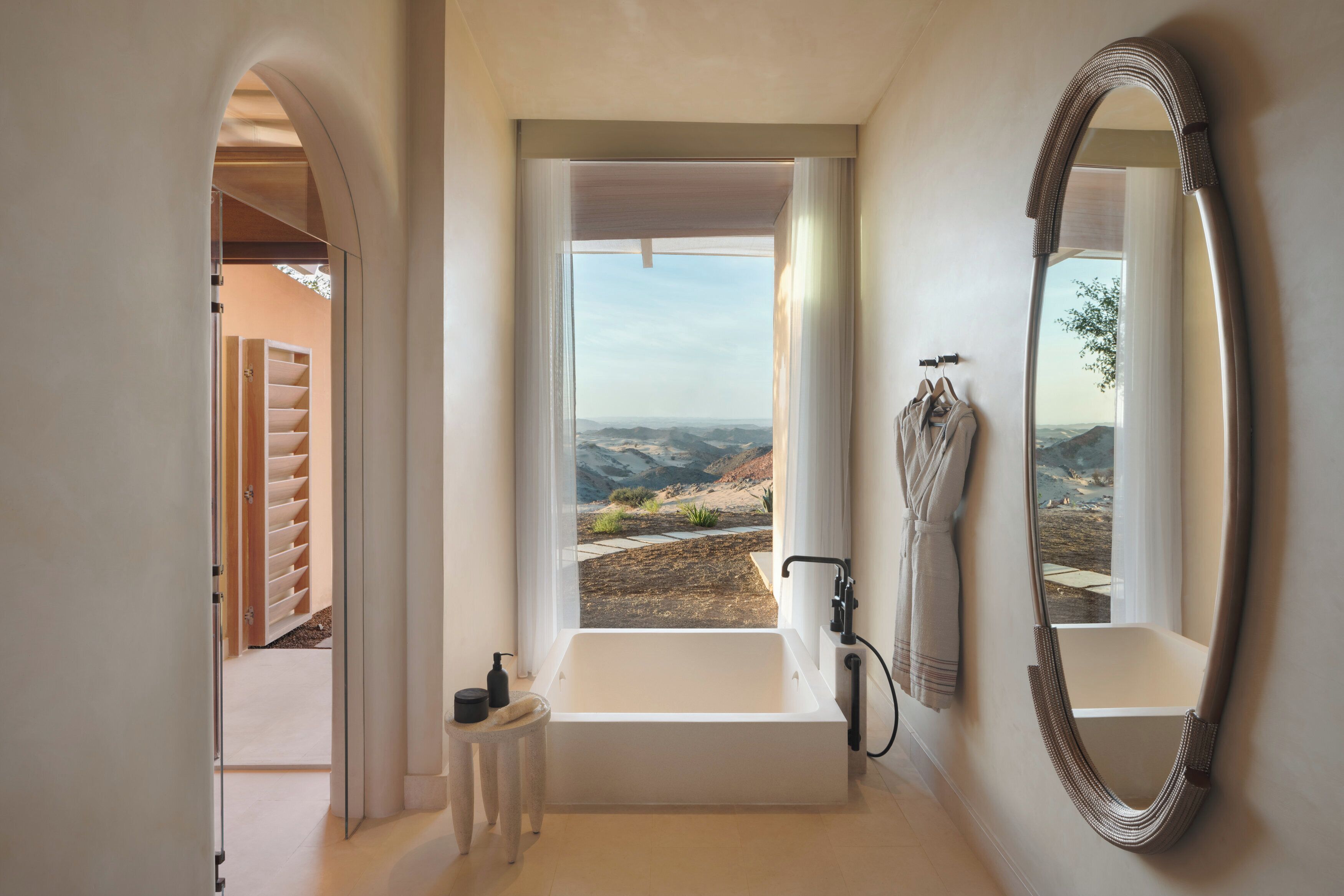 Un baño con bañera, un espejo grande y vistas a un paisaje montañoso.