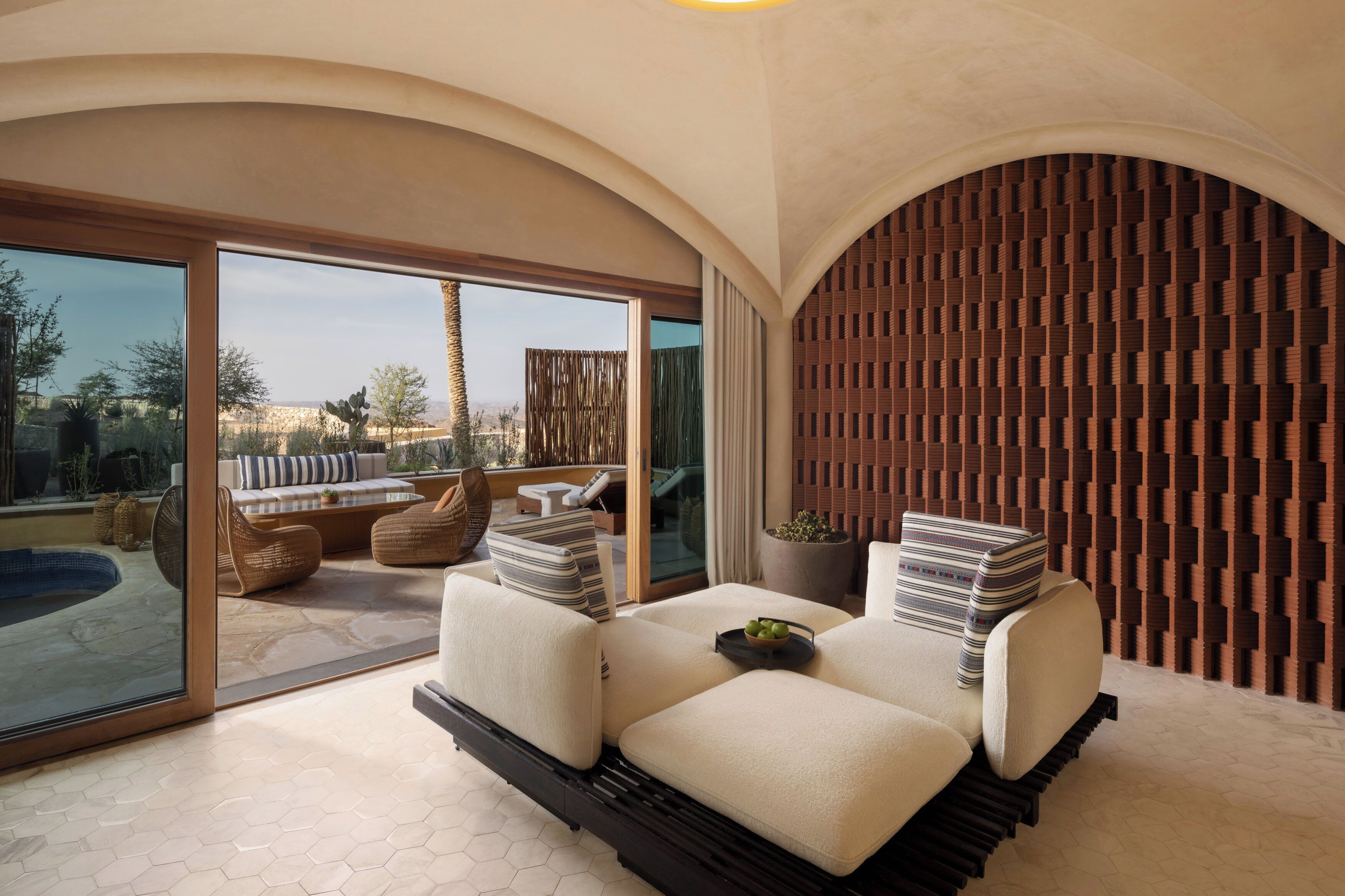 A modern lounge area with a sofa set, a pool, and a view of the outdoors.