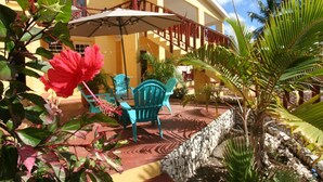 Un espace patio aménagé avec une table et des chaises, un grand parasol et un mur en pierre.