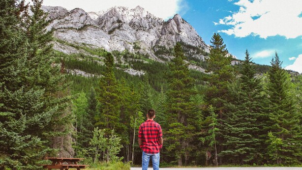A person standing in front of a picnic table with a mountainous background. - Sundance Family Tipi (Kananaskis)