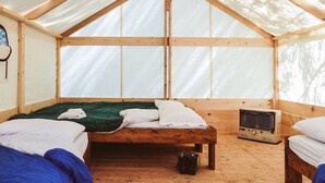 Una stanza a tenda con un letto di legno, un termosifone e una finestra.