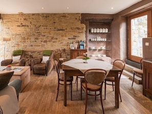 A cozy dining area with a stone wall, wooden furniture, and a view through a window.