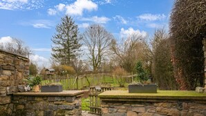 A stone wall with a wooden bench and planters. - Tranquil Home in Tinlot (Tinlot)