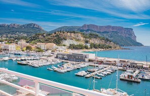 A marina with numerous boats docked, a building with a sign, and a mountainous backdrop.