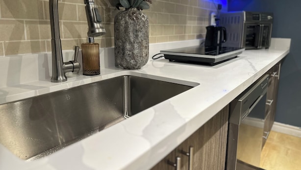 A modern kitchen with a stainless steel sink, a marble countertop, and a built-in range hood. - Walkout 1 Beb, 1 Bath Bsmnt Apt (Ajax)