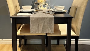 A dining table with two chairs, a decorative wall piece, and a vase with flowers. - Walkout 1 Beb, 1 Bath Bsmnt Apt (Ajax)