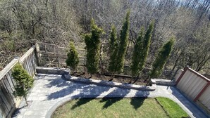 A backyard with a paved patio, a small lawn, and a wooden fence. - Walkout 1 Beb, 1 Bath Bsmnt Apt (Ajax)