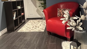 A modern living room with a red sofa, a black bookshelf, a white rug, and decorative wall art. - Walkout 1 Beb, 1 Bath Bsmnt Apt (Ajax)