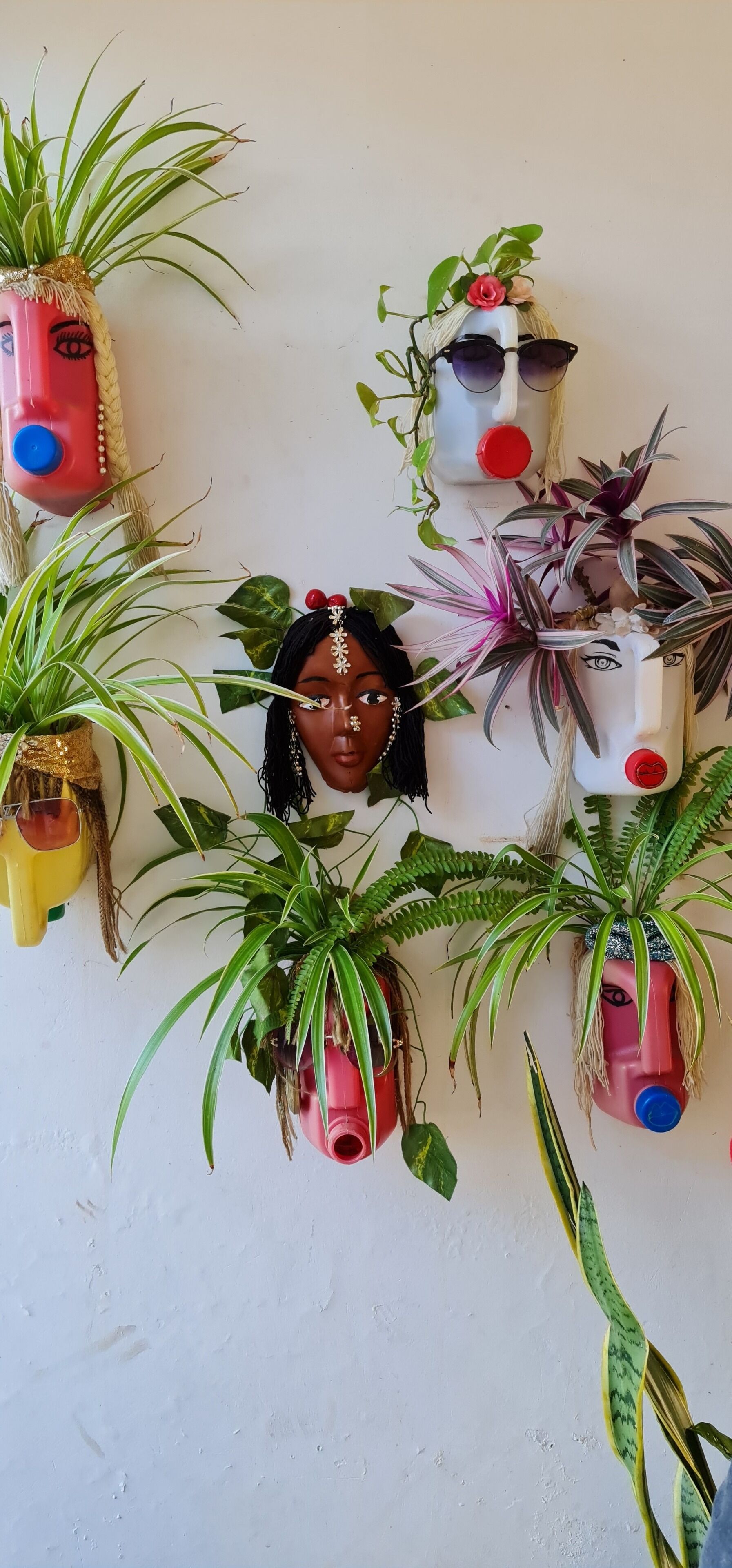 A wall decorated with potted plants and masks.