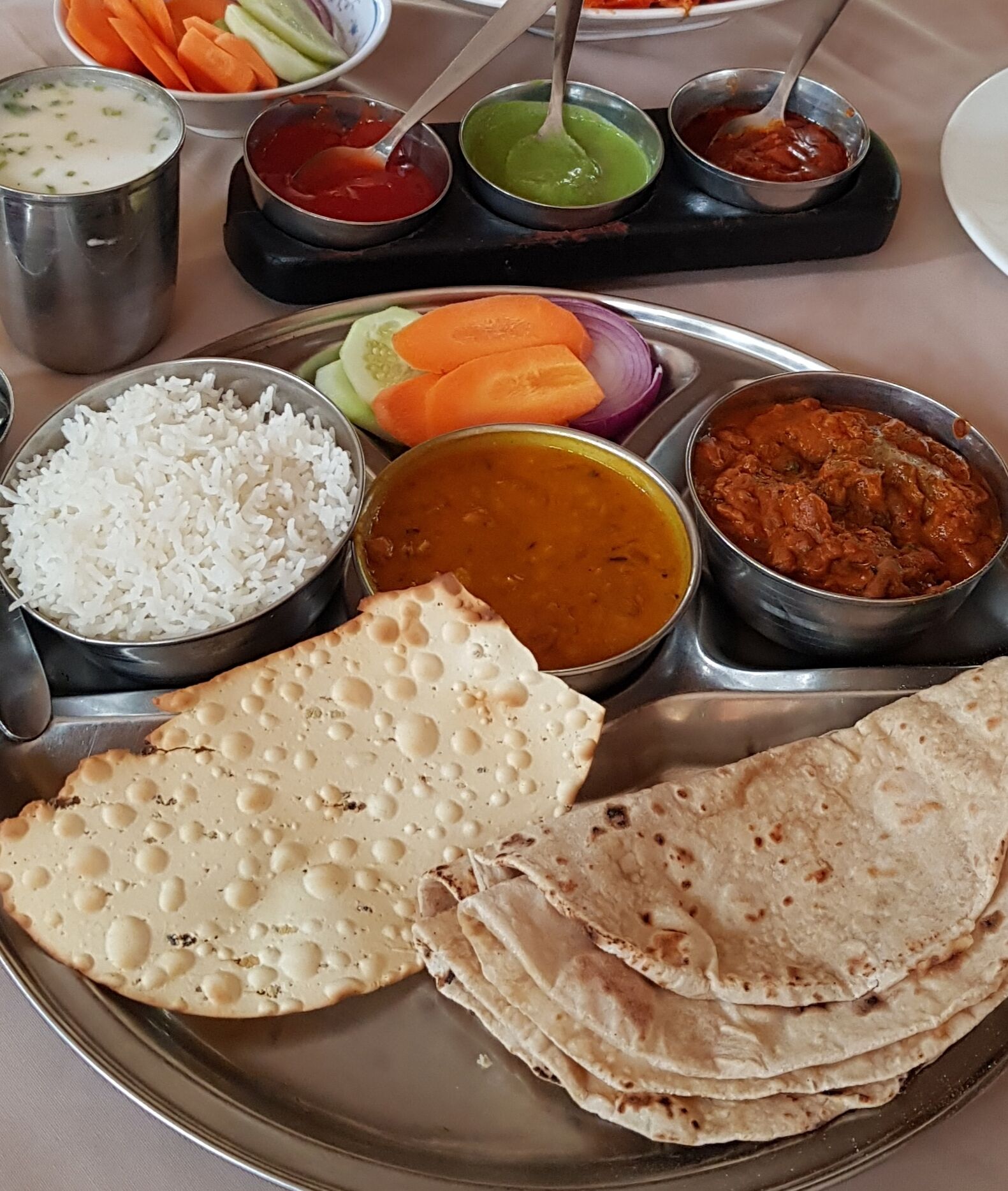 Comida con arroz, curry y panes planos sobre un plato de metal.