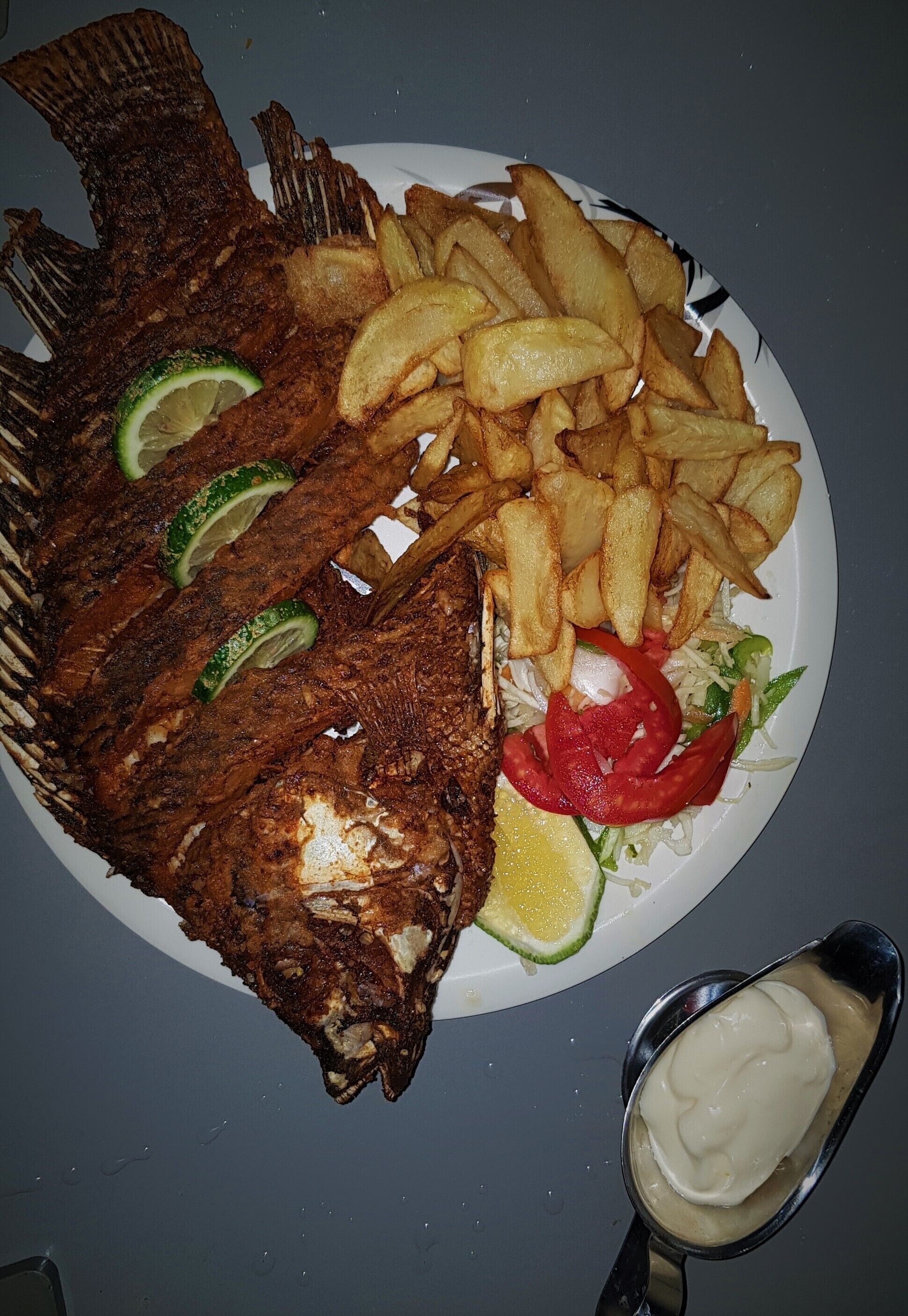 A plate with fried fish, fries, and a salad.