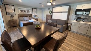 Un espace de vie moderne et compact comprenant un coin repas, une kitchenette et une chambre.
