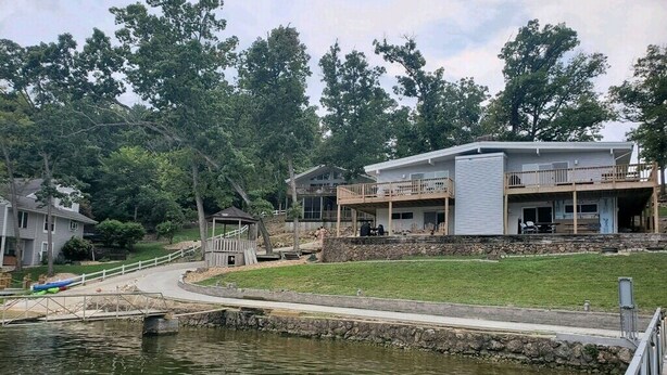 Une propriété située au bord de l’eau, avec une grande maison dotée d’un patio couvert et d’un mur de soutènement en pierre.