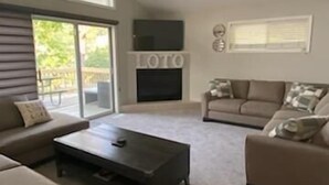 Una sala de estar amplia con un gran ventanal, chimenea y ventilador de techo.