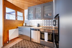 Une cuisine moderne avec un plafond en bois, un lave-vaisselle encastré et un réfrigérateur en acier inoxydable.