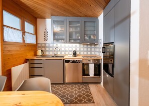 Cocina compacta con armarios de madera, horno empotrado y microondas.