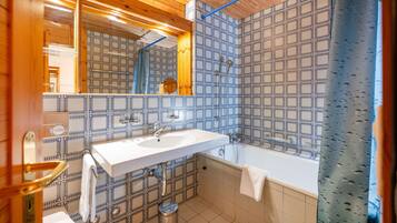 Ein Badezimmer mit weißem Waschbecken, einem Spiegel, einer Badewanne und einer Dusche.