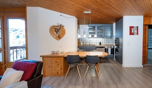 Eine moderne Küche mit Holzboden, ein Essbereich mit Holztisch und -stühlen sowie eine herzförmige Dekoration an der Wand.