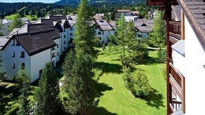 A residential area with white buildings, green lawns, and a mountainous backdrop. - Apartment with mountain view and spa access (Lenzerheide/Lai)