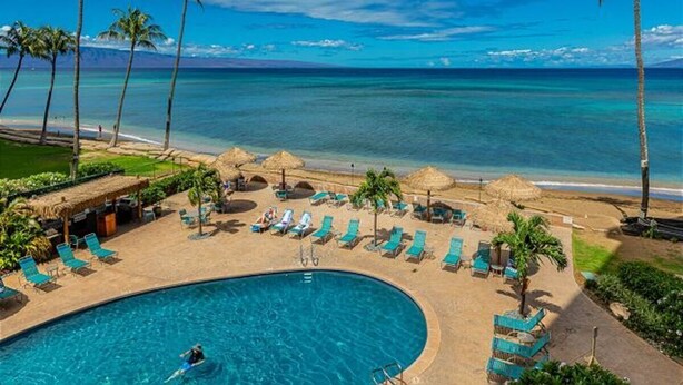 A resort pool area with a view of the ocean, lounge chairs, and palm trees. -   Dlx OCEANVIEW Maui  Studio..Updated!
West Maui. AC. Royal Kahana. (Lahaina)