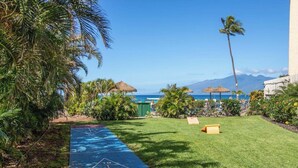 A well-maintained garden with a shuffleboard court, palm trees, and a view of the ocean. -   Dlx OCEANVIEW Maui  Studio..Updated!
West Maui. AC. Royal Kahana. (Lahaina)