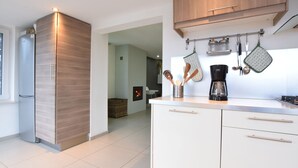 Een moderne keuken met een inbouwoven, een koffiezetapparaat en hangend keukengerei.
