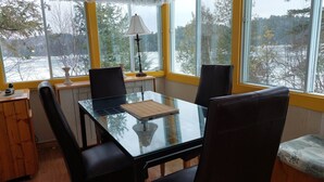 Een eetruimte met een glazen tafel, zwarte stoelen en een lamp.